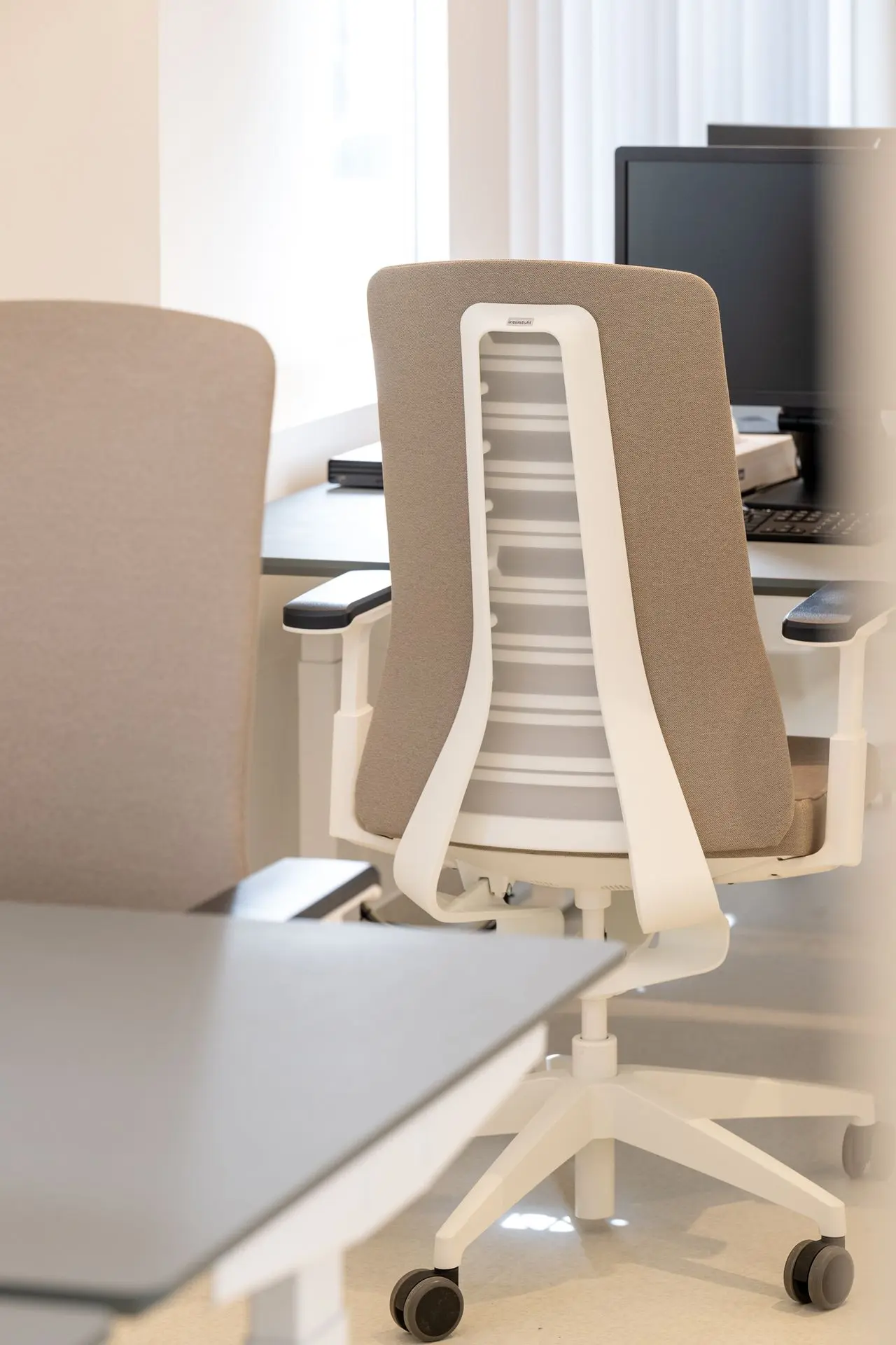 Ergonomische bureaustoelen aan moderne werkplekken in de vernieuwde longartsenpraktijk van Sint-Truiden.