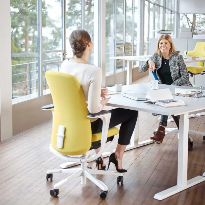 HÅG SoFi 7300 met gestoffeerde rugleuning in een lichte overleg- of vergaderruimte Gele HÅG SoFi 7300 bureaustoel aan vergadertafel