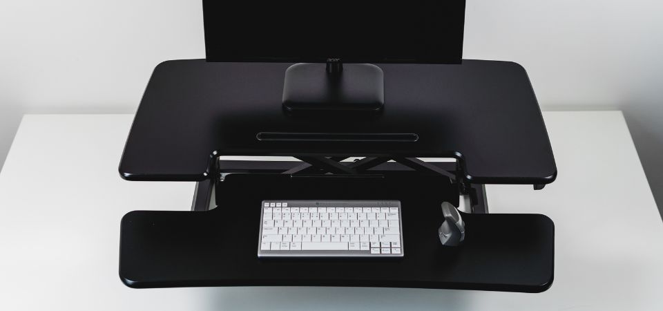 Close-up van de dubbele platforms van de Adjustable Sit-Stand Desk Riser 2, met DXT-muis en UltraBoard 950. Detail van de zwarte Adjustable Sit-Stand Desk Riser 2 met twee niveaus, inclusief een DXT-muis en een UltraBoard 950 toetsenbord.